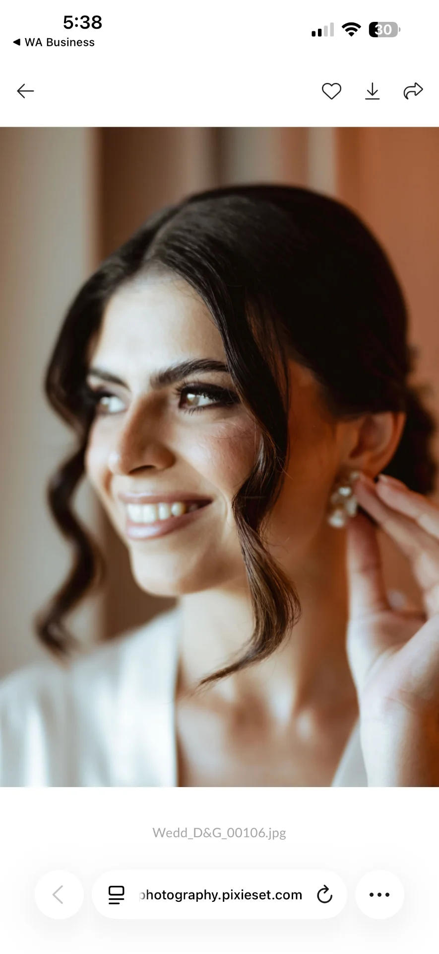 Primer plano de la novia sonriendo mientras ajusta su arete