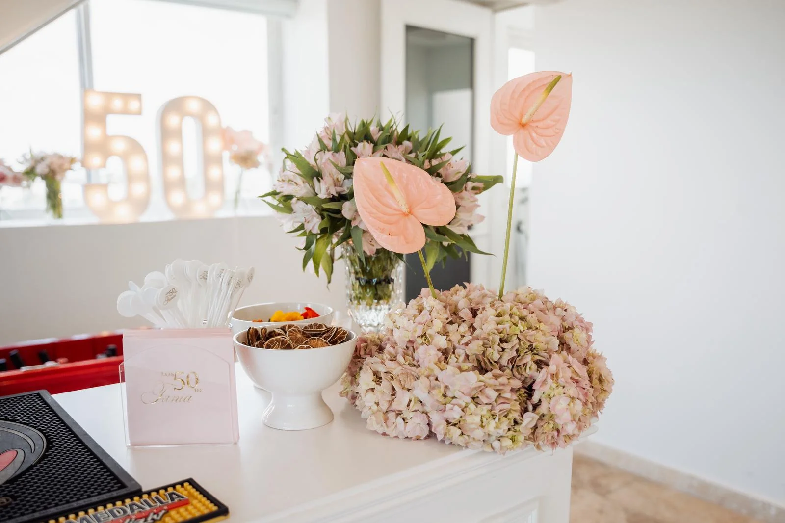 Mesa de postres con flores y decoraciones en tonos rosados