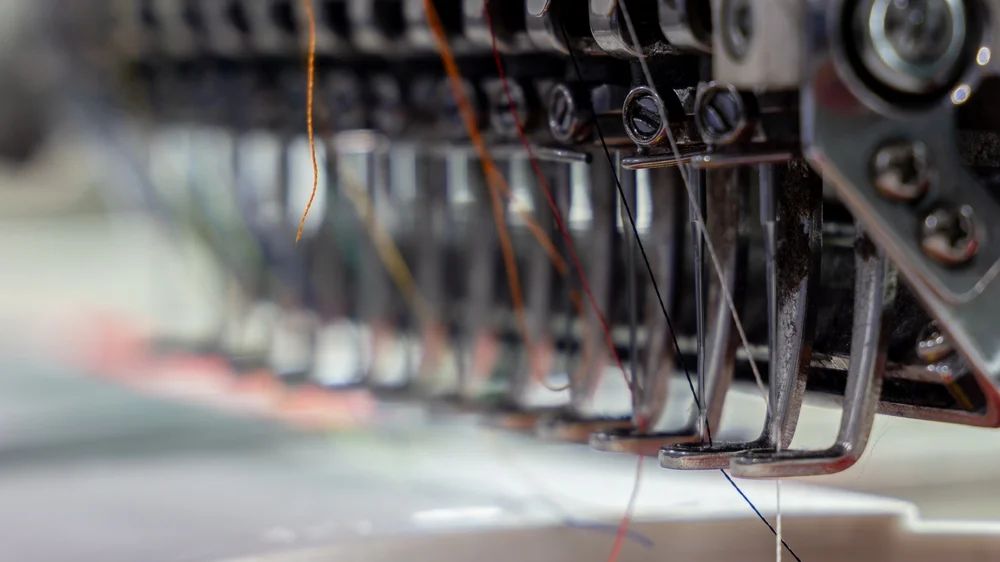 Máquina de bordado industrial trabajando sobre una prenda